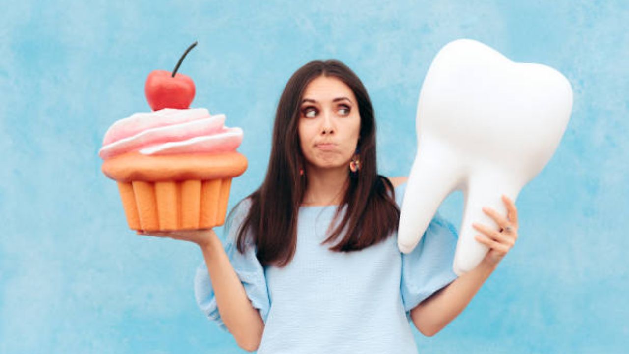 Mulher segurando representação de dente em uma mão e na outra, uma representação de um cupcake 