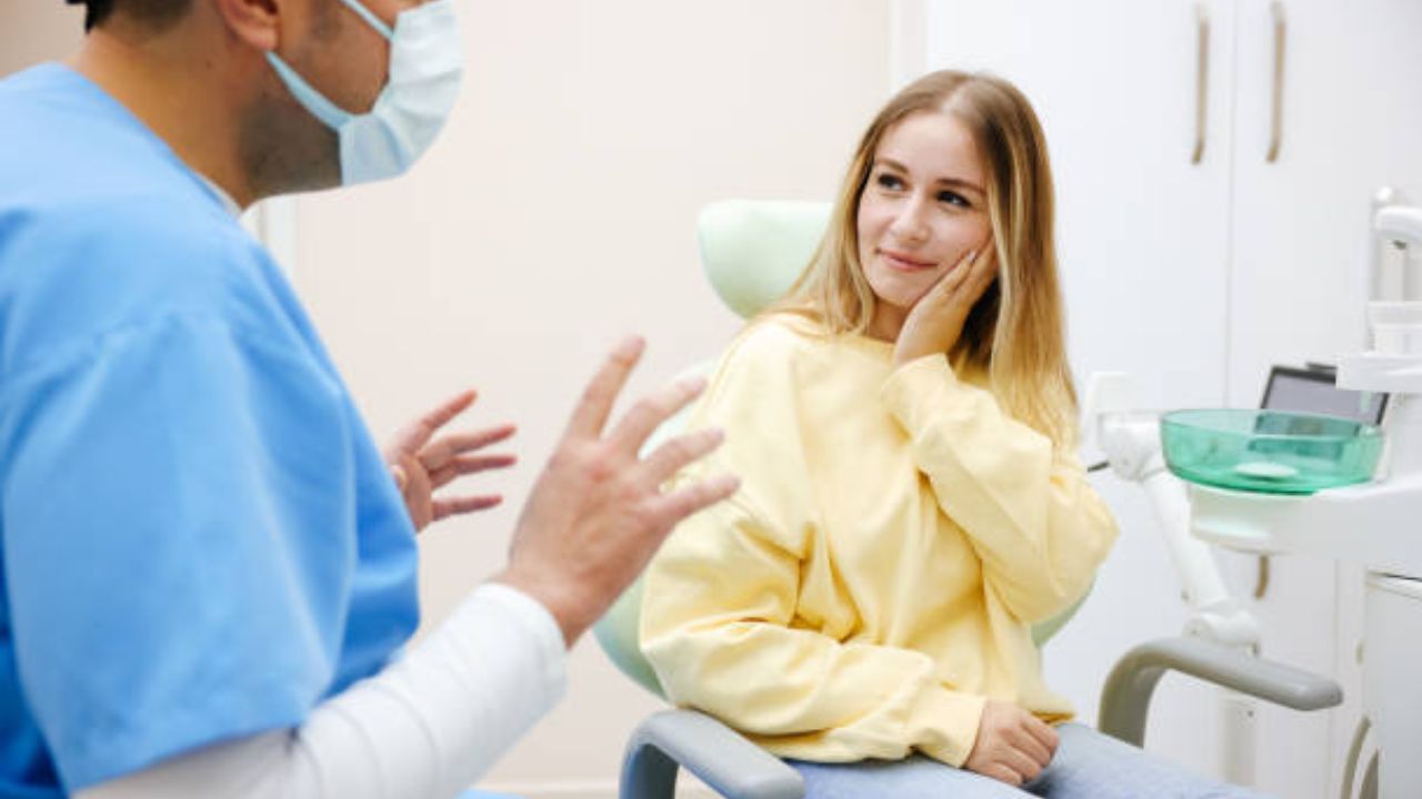 Paciente em consultório odontológico com mão no rosto com queixa de dor por trismo