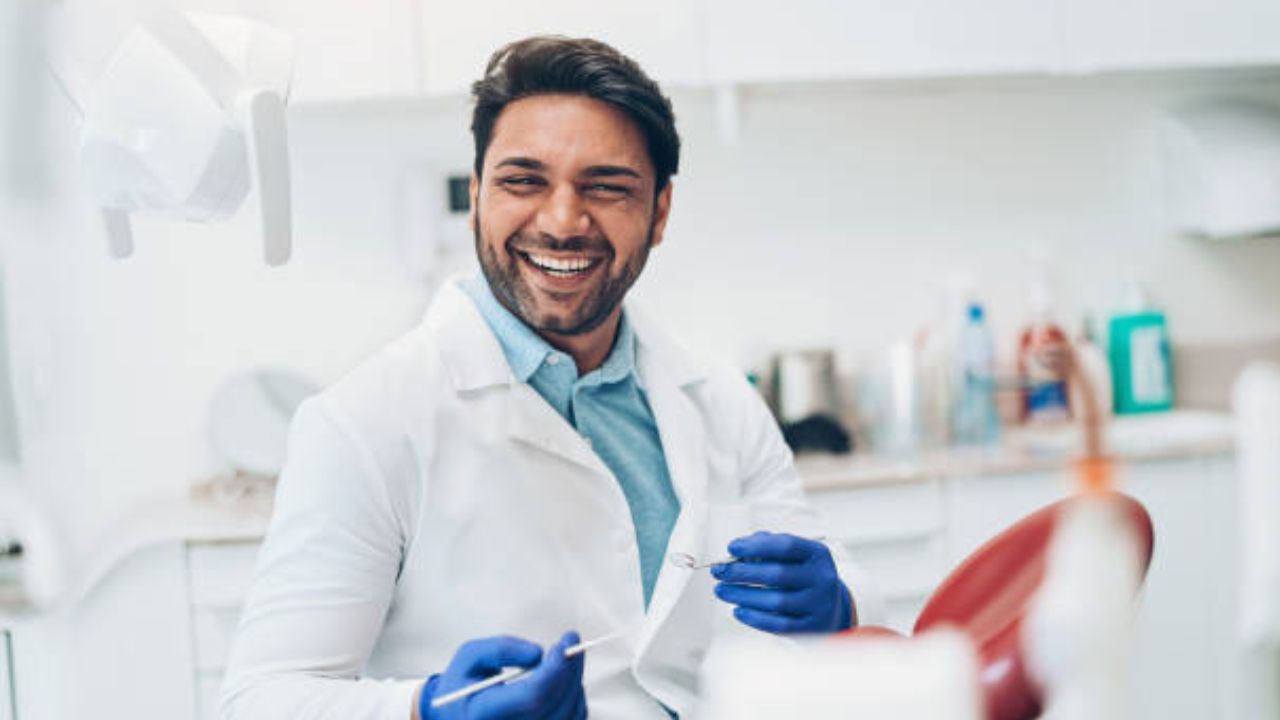 Dentista sorrindo segurando alguns instrumentos odontológicos