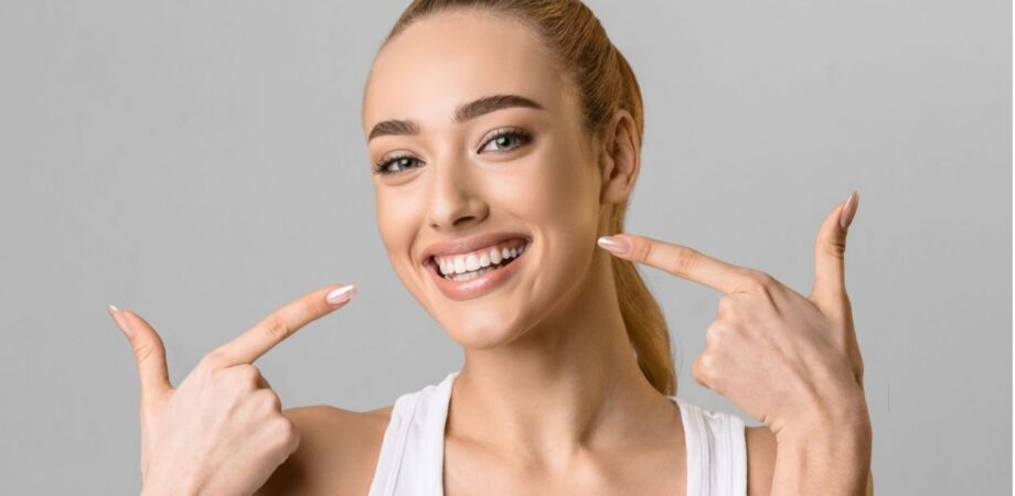 Mulher sorrindo apontando para sorriso com lente de contato dental