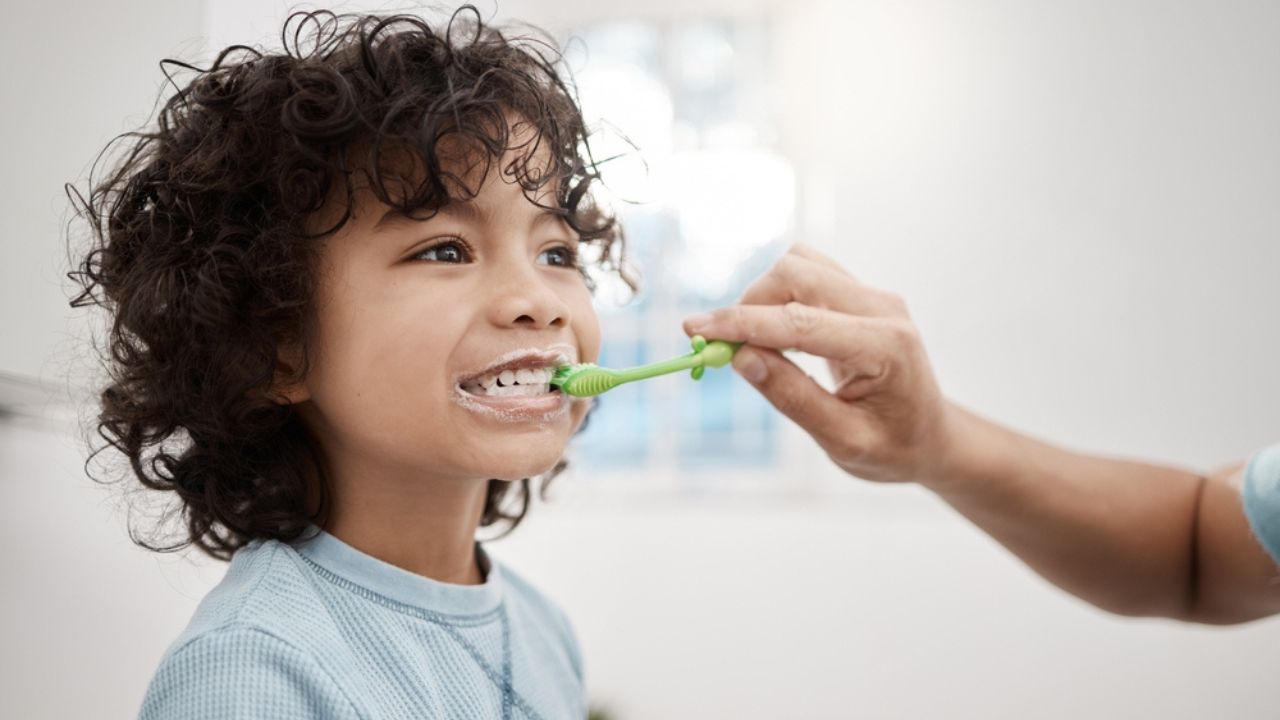 adulto escovando os dentes da criança para prevenir a gengivite infantil