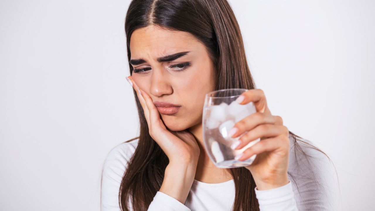 paciente bebendo água gelada e sentindo sensibilidade nos dentes