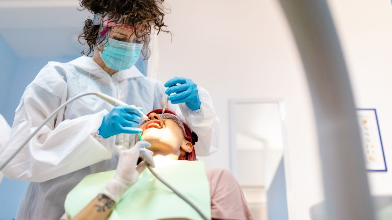 Paciente mulher deitada em maca de consultório de dentista recebendo tratamento de periodontite