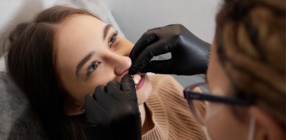 Uma moça recebendo cuidados de um profissional em piercing inflamado na gengiva.