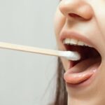 Profissional de saúde analisando saliva de boca de paciente mulher com contonete