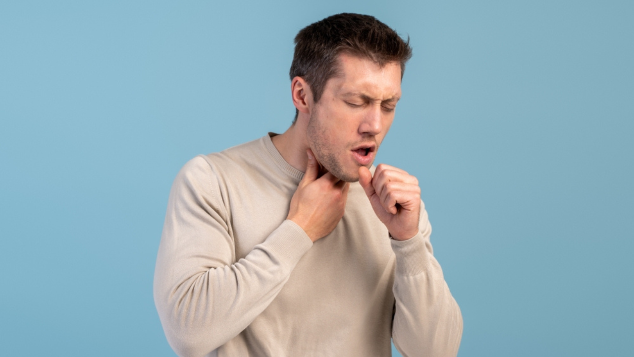 Um homem tossindo, um dos sintomas de HPV na garganta.