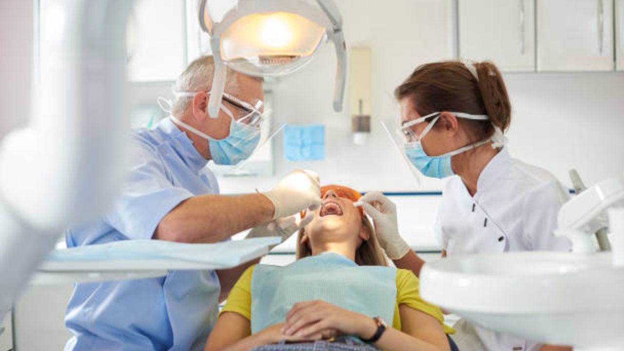Ortodontistas avaliando zona bucal de paciente mulher em consultório odontológico