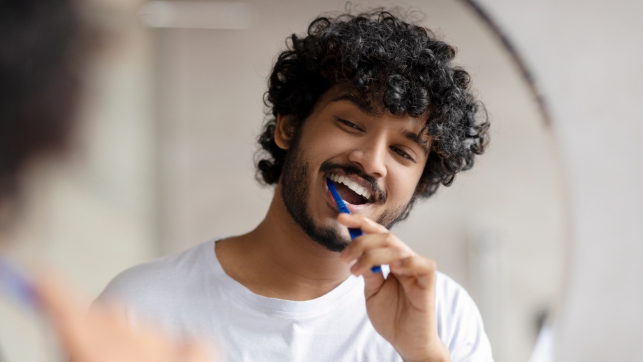 Um jovem realizando cuidados com a saúde bucal através da escovação dos dentes, promovendo a saúde da glândula salivar.