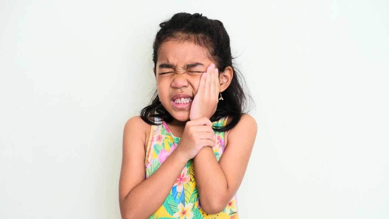 Uma menina sentindo dores nos dentes provenientes de doença pulpar.