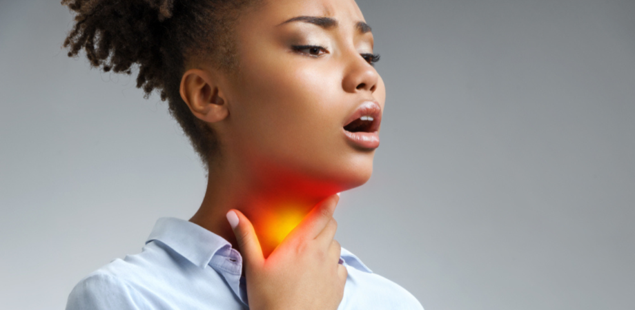 Uma jovem sentindo dores na garganta, um dos sintomas de quem apresenta pus na garganta.