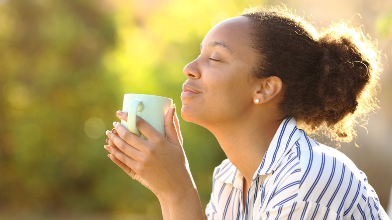 Uma moça tomando chá ao ar livre, como alternativa caseira para tosse seca.