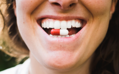 Mulher sorrindo com pílula antibiótica de terramicina entre os dentes.