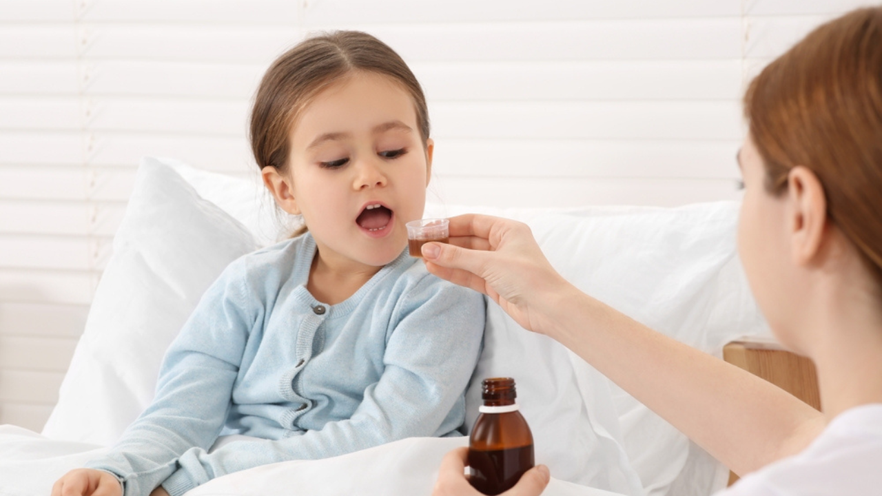 Uma criança tomando um xarope infantil para tosse seca.